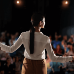 Mulher fazendo palestra para auditório com pessoas
